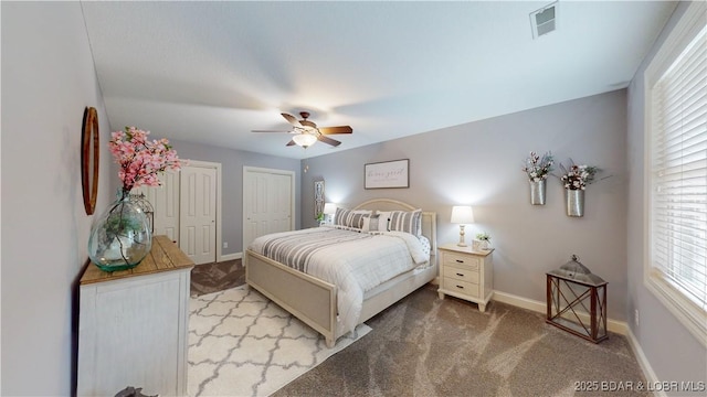 carpeted bedroom featuring multiple closets and ceiling fan