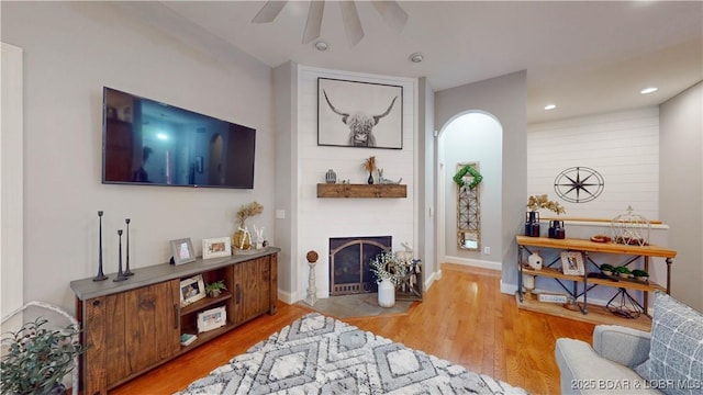 living area featuring a fireplace, recessed lighting, a ceiling fan, wood finished floors, and baseboards