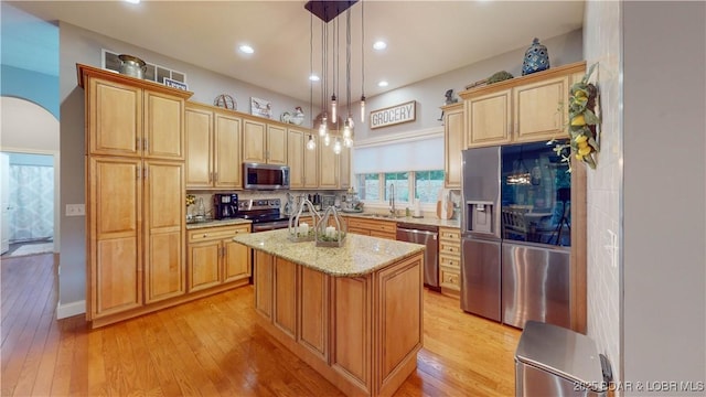 kitchen featuring sink, hanging light fixtures, a kitchen island with sink, light stone counters, and stainless steel appliances