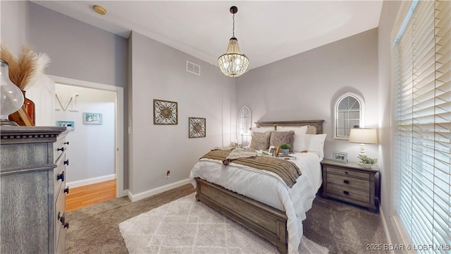 carpeted bedroom featuring baseboards, visible vents, and a chandelier