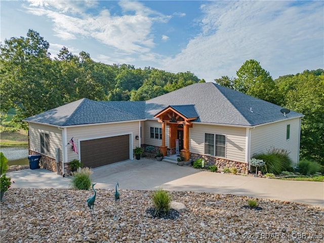 ranch-style house featuring a shingled roof, stone siding, an attached garage, and concrete driveway