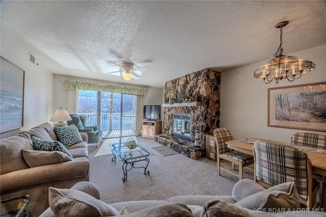 carpeted living room with a textured ceiling, a fireplace, and ceiling fan with notable chandelier