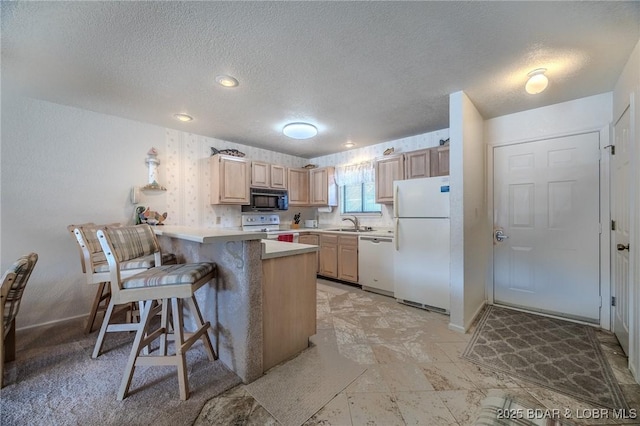 kitchen with kitchen peninsula, a breakfast bar area, light brown cabinets, white appliances, and sink