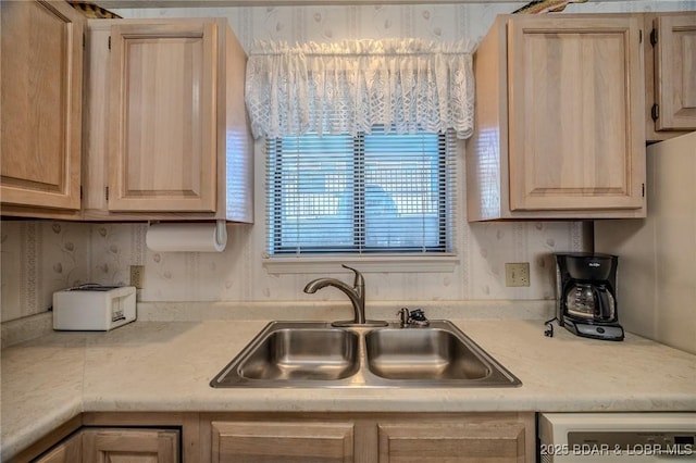 kitchen featuring light brown cabinetry, dishwashing machine, and sink