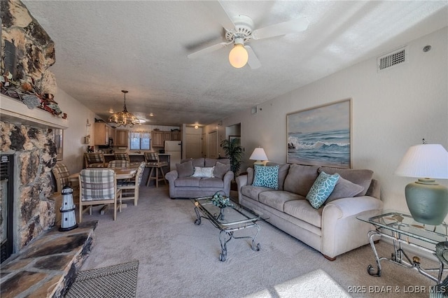 carpeted living room with a textured ceiling and ceiling fan with notable chandelier