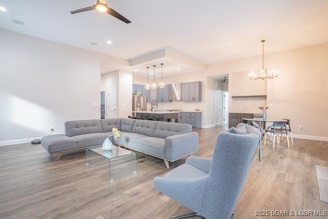 living room featuring light wood-type flooring and ceiling fan with notable chandelier