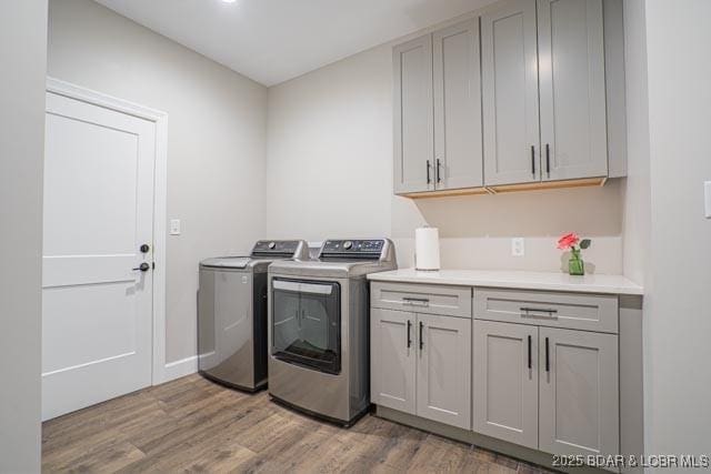 laundry area with cabinets, light hardwood / wood-style flooring, and washing machine and dryer