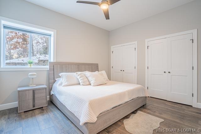 bedroom featuring ceiling fan, two closets, and hardwood / wood-style flooring