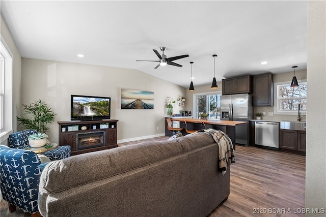 living room featuring vaulted ceiling, ceiling fan, wood-type flooring, and sink