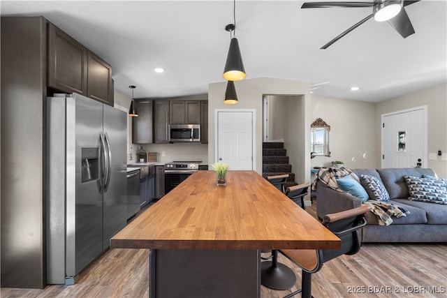 kitchen with dark brown cabinetry, a kitchen island, stainless steel appliances, and pendant lighting