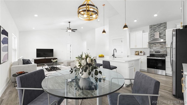 dining space with ceiling fan, lofted ceiling, light hardwood / wood-style flooring, and sink