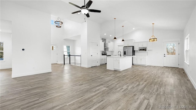 unfurnished living room with light wood-type flooring, ceiling fan, plenty of natural light, and sink