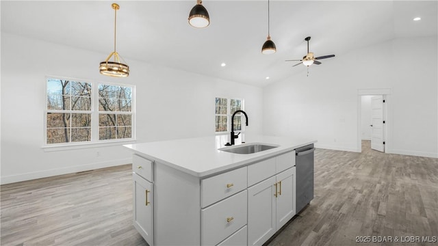 kitchen with vaulted ceiling, a center island with sink, stainless steel dishwasher, sink, and ceiling fan with notable chandelier