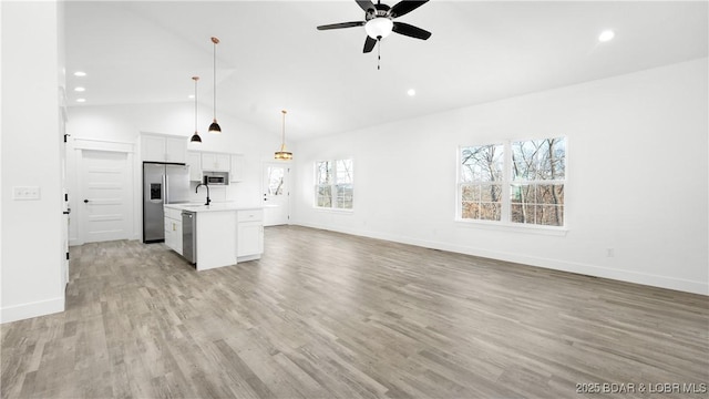 kitchen with a center island with sink, ceiling fan, appliances with stainless steel finishes, pendant lighting, and white cabinets