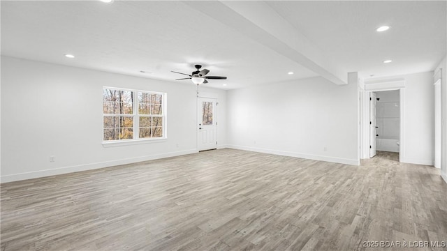 spare room with ceiling fan, beamed ceiling, and light wood-type flooring