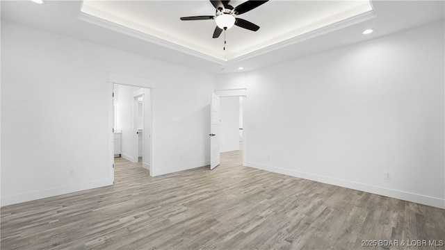 interior space with ceiling fan, light hardwood / wood-style flooring, and a raised ceiling