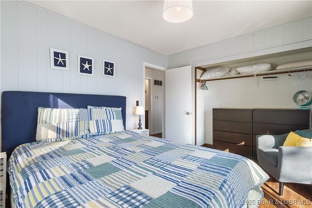 bedroom with a closet and wood walls