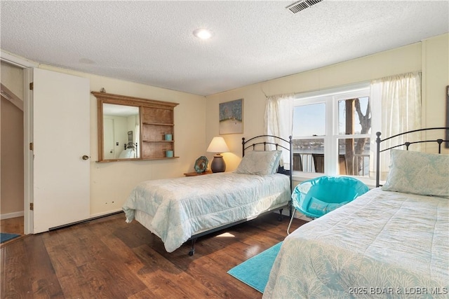 bedroom with dark hardwood / wood-style floors and a textured ceiling