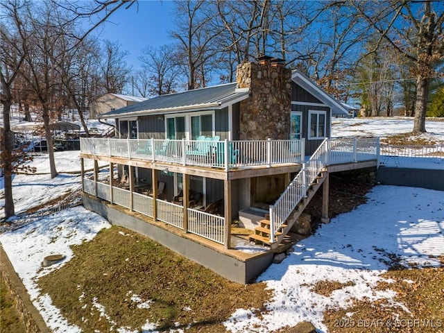 snow covered back of property with a wooden deck