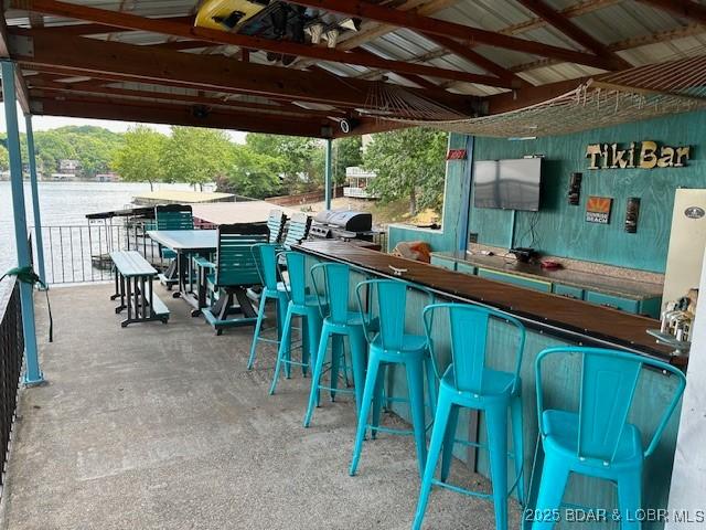 view of patio with exterior bar and a water view