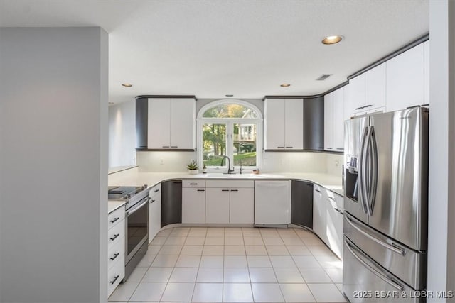 kitchen with white cabinetry, stainless steel appliances, decorative backsplash, sink, and light tile patterned flooring