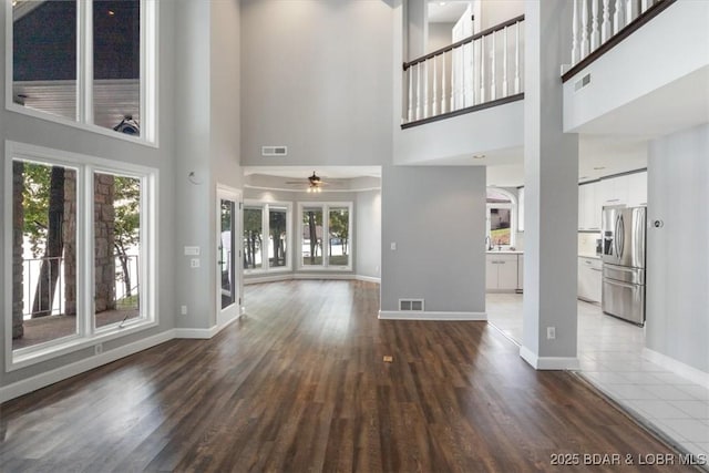 unfurnished living room with ceiling fan, a high ceiling, and hardwood / wood-style floors