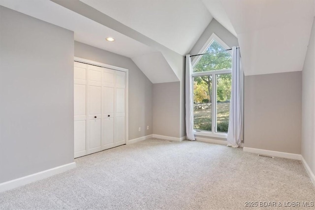 additional living space with light carpet and vaulted ceiling