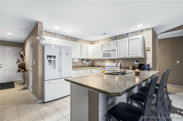 kitchen with a kitchen bar, kitchen peninsula, white appliances, white cabinets, and sink