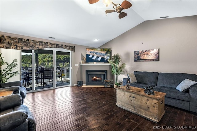 living area with vaulted ceiling, a ceiling fan, wood finished floors, a fireplace with flush hearth, and visible vents