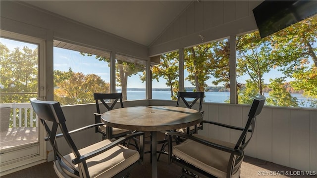 sunroom / solarium featuring a healthy amount of sunlight, a water view, and vaulted ceiling