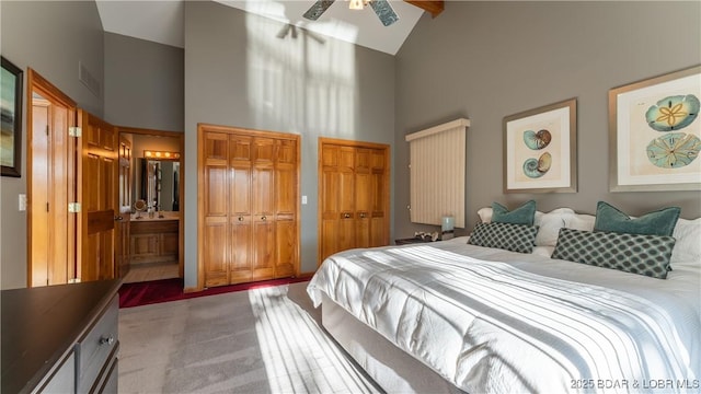 bedroom featuring high vaulted ceiling, ensuite bath, multiple closets, and ceiling fan