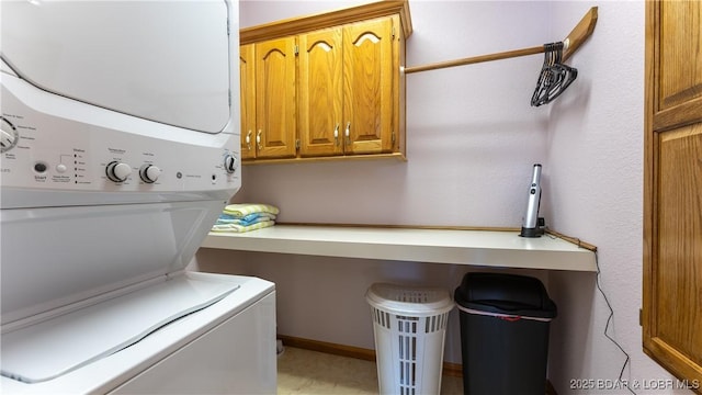 clothes washing area featuring cabinets and stacked washer and clothes dryer