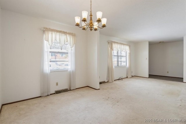 carpeted spare room with a chandelier