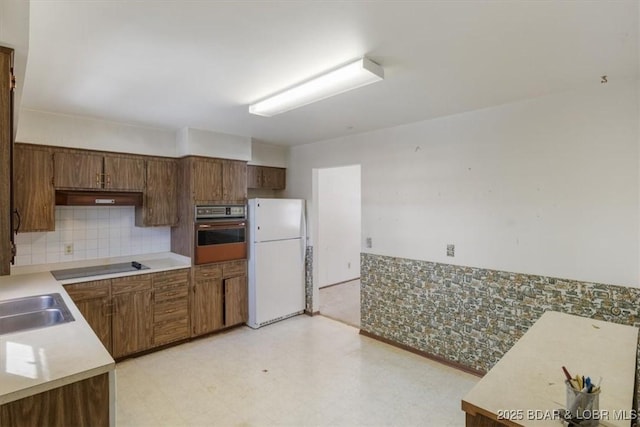 kitchen with wall oven, black electric stovetop, ventilation hood, white refrigerator, and sink