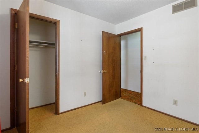 unfurnished bedroom with light colored carpet and a closet