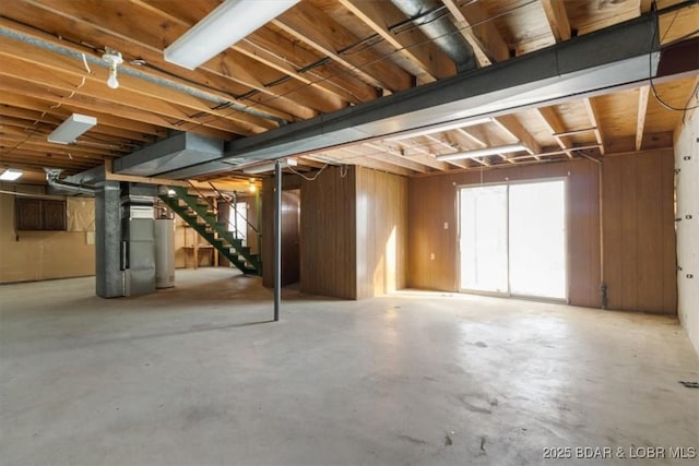 basement with heating unit, wooden walls, and gas water heater