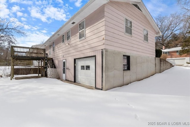 view of snowy exterior with a garage and a wooden deck