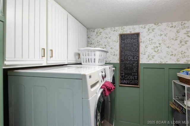 laundry room with cabinets, a textured ceiling, and washer and clothes dryer