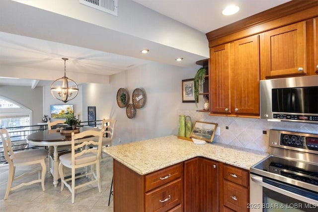 kitchen featuring stainless steel appliances, light stone countertops, a notable chandelier, and kitchen peninsula