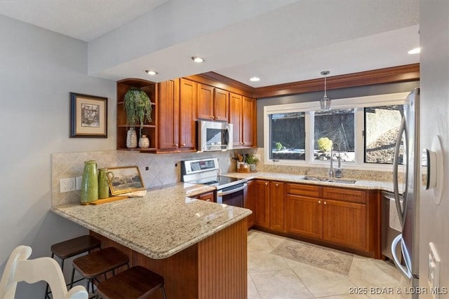 kitchen with sink, a breakfast bar area, hanging light fixtures, appliances with stainless steel finishes, and kitchen peninsula