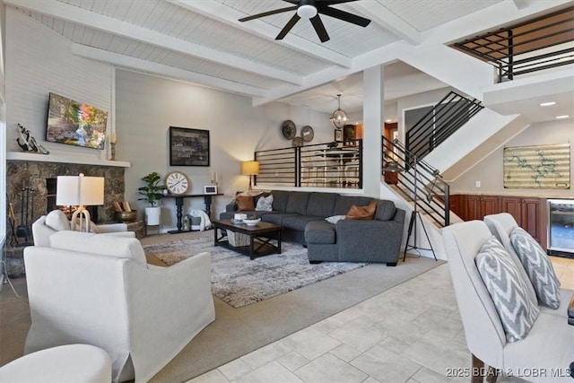 living room with beamed ceiling, beverage cooler, and ceiling fan with notable chandelier