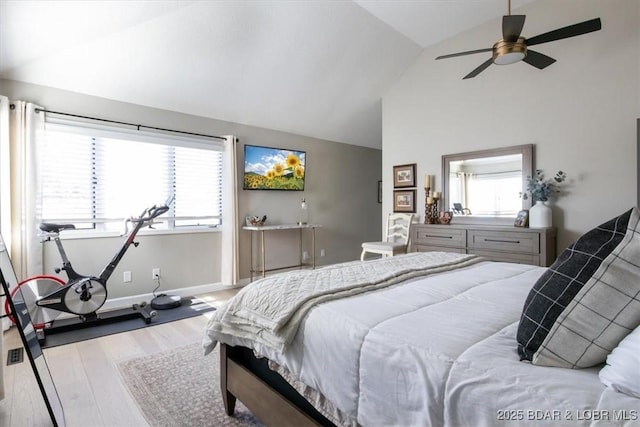 bedroom with multiple windows, lofted ceiling, ceiling fan, and light hardwood / wood-style flooring