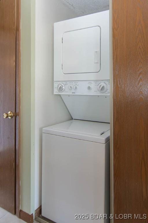 laundry room featuring stacked washer / drying machine and a textured ceiling