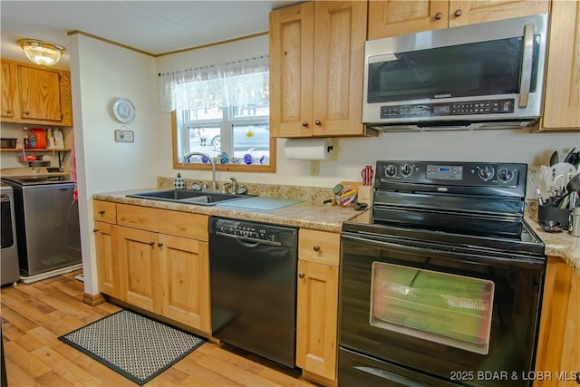 kitchen featuring light hardwood / wood-style floors, sink, black appliances, and washing machine and clothes dryer