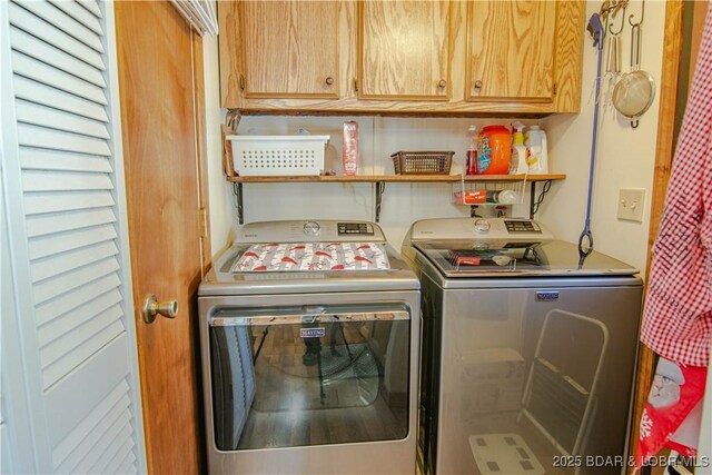 clothes washing area with cabinets and washing machine and dryer