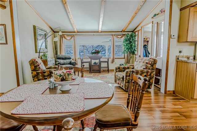 dining room featuring light hardwood / wood-style flooring and lofted ceiling with beams