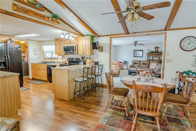 kitchen featuring black appliances, a kitchen bar, light brown cabinets, sink, and light hardwood / wood-style flooring