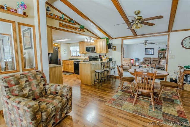 dining room with sink, lofted ceiling with beams, and light wood-type flooring