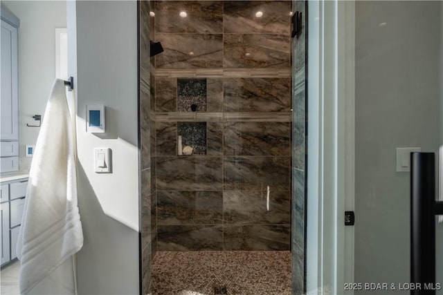 bathroom with tiled shower and vanity