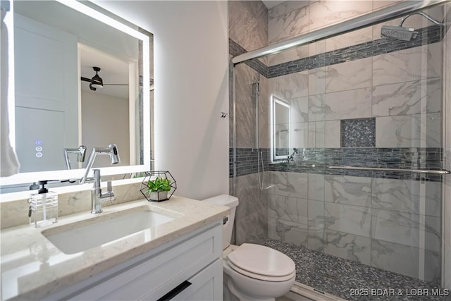 bathroom featuring toilet, ceiling fan, an enclosed shower, and vanity